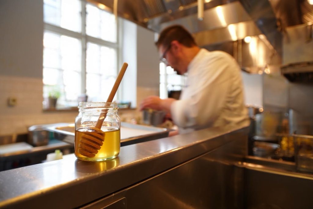 cuisinier professionnel qui utilise du miel pour ses recettes