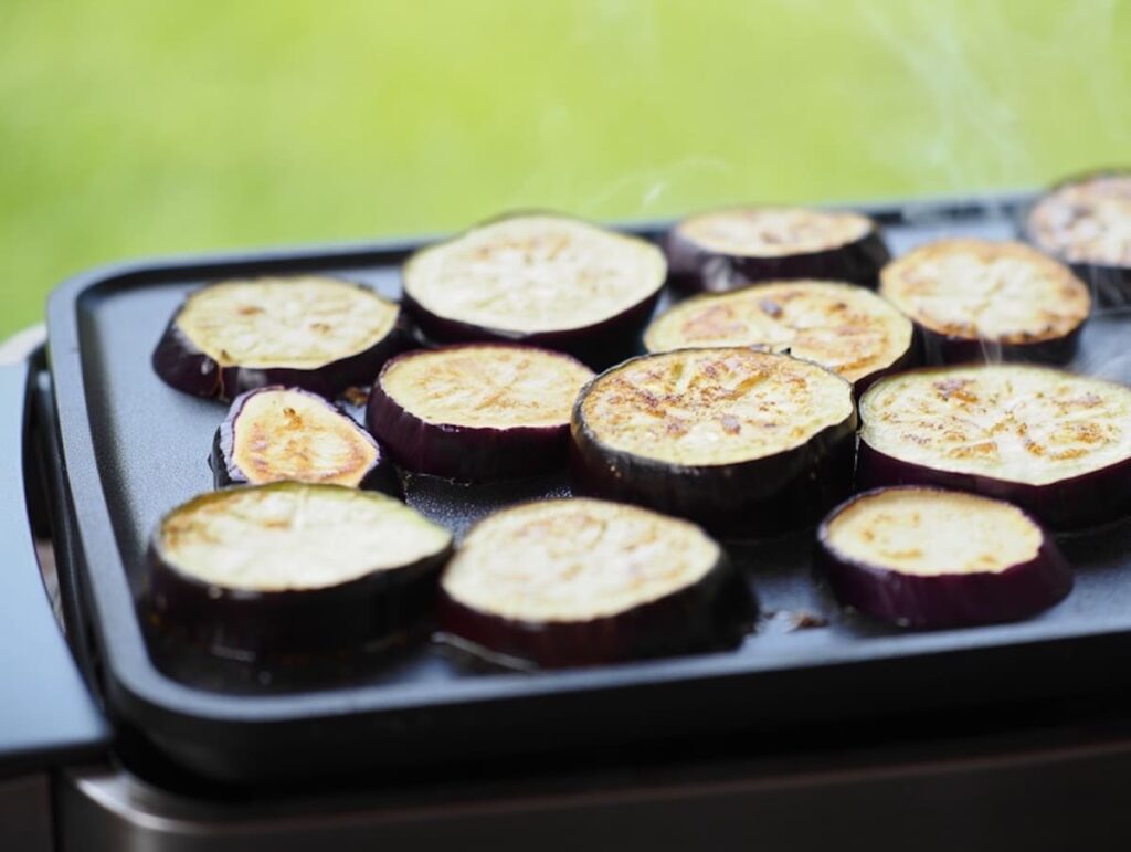 rondelles d'aubergines en train de cuire sur une plancha